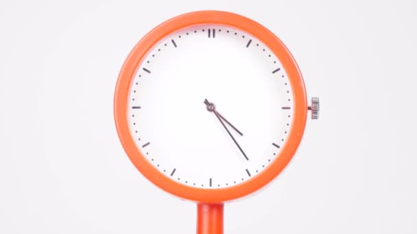 Oranssi kello näyttää ajan kulumisen. Kellon käsien liike kulki nopeasti. Valkoisella pohjalla. - Materiaali, video