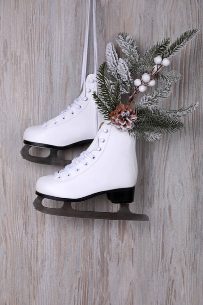 Pair of ice skates with Christmas decor hanging on wooden wall - Фото, изображение