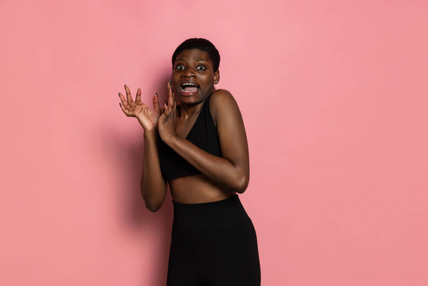 Studio shot of young scared african woman standing alone isolated on pink studio background with copyspace for ad. - Foto, imagen