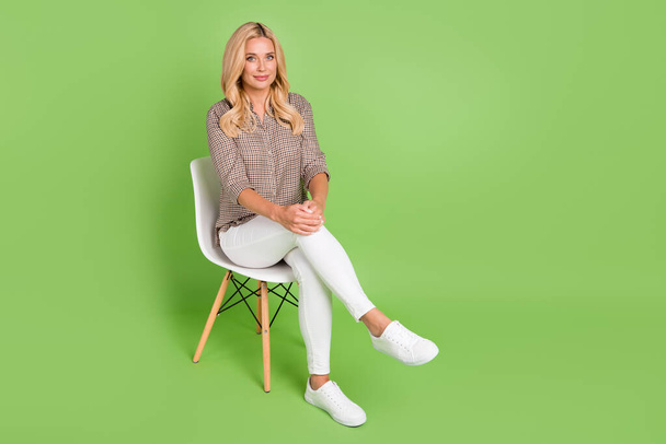 Portrait de contenu attrayant femme joyeuse assise sur une chaise de bureau en attente d'un emploi espace de copie d'entrevue isolé sur fond de couleur vert vif. - Photo, image
