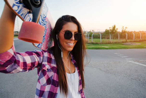 Beautiful and fashion young woman posing with a skateboard. - Фото, изображение