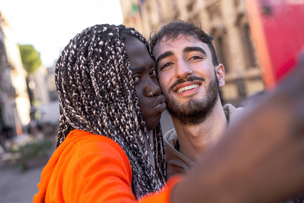 Multiracial couple taking selfie in the street - 写真・画像
