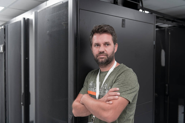 Portrait of male technician or network administrator standing brave as a hero with arms crossed in data center server room. High quality photo - Foto, Bild