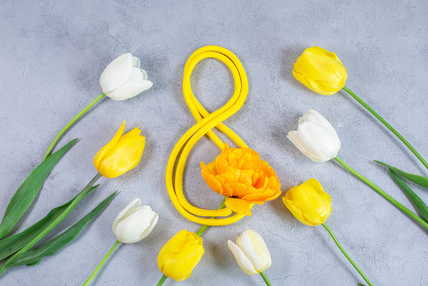 White and yellow tulips and yellow ribbon in the shape of number 8. - Фото, изображение