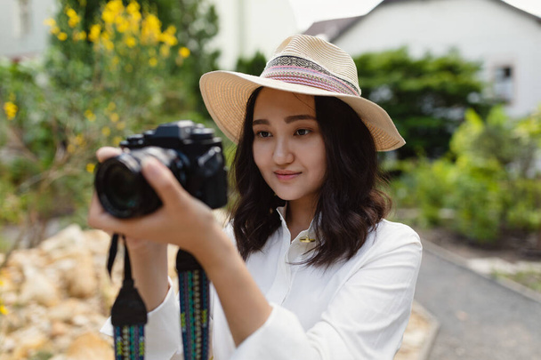 Young Asian woman in a park holding camera, outdoor portrait - 写真・画像