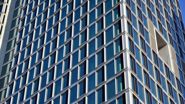 Geschäftshäuser in blauem Ton. Gigantischer Wolkenkratzer von unten. Architektonische Details des modernen Gebäudes amd Glasfassade. Geschäftshintergrund an einem schönen sonnigen Tag.  - Foto, Bild