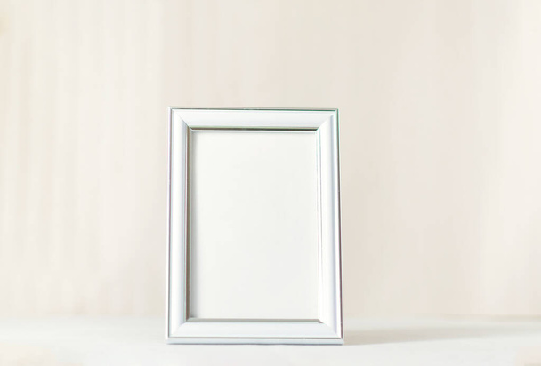 Blank white picture frame on a plain beige background. Empty poster mockup for art display. No people - Фото, изображение