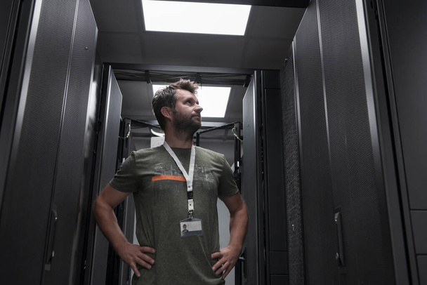 Portrait of male technician or network administrator standing brave as a hero with arms crossed in data center server room. High quality photo - Foto, Imagen