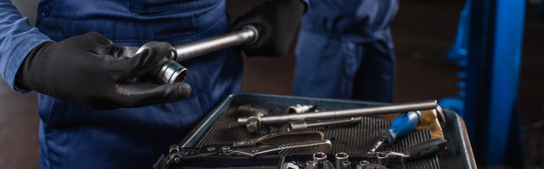 Cropped view of mechanic in uniform and gloves holding wrench in car service, banner  - Zdjęcie, obraz