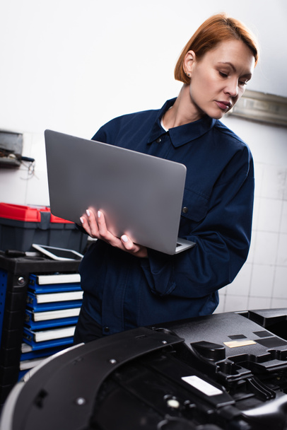forewoman with laptop making diagnostics of car in workshop - Foto, immagini