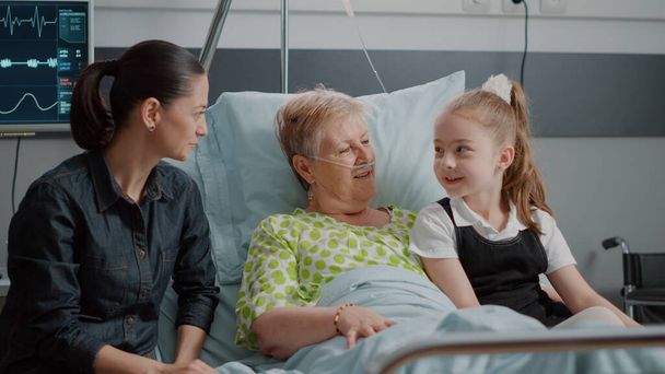 Chorym emerytem korzystających z wizyty od siostrzenicy i córki w szpitalu oddział łóżko - Zdjęcie, obraz