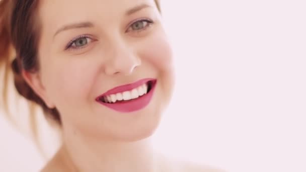 Retrato de cara de belleza de mujer joven sonriendo, perfecta sonrisa de dientes blancos, maquillaje glamuroso con cosméticos naturales, modelo caucásico hermoso posando para el cuidado de la piel y el maquillaje - Metraje, vídeo