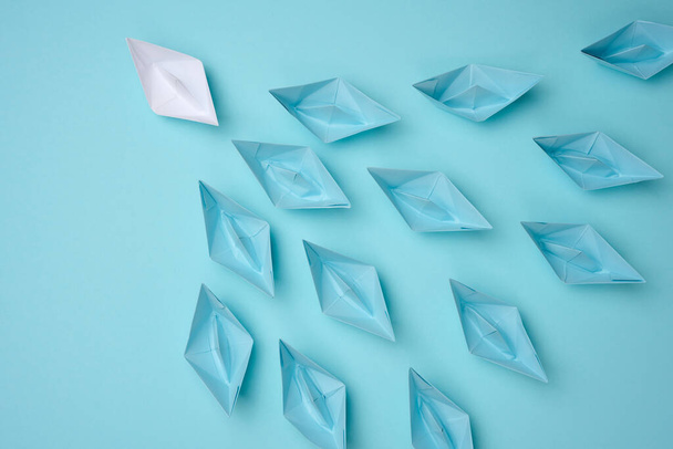 a group of blue paper boats follow white against a light blue background. Strong leader concept, mass manipulation. Starting a business with a well-coordinated team, start-up - Fotoğraf, Görsel