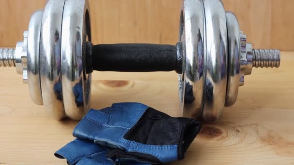 Healthy lifestyle. Dumbbells on a wooden background. Gloves for sports - Filmati, video