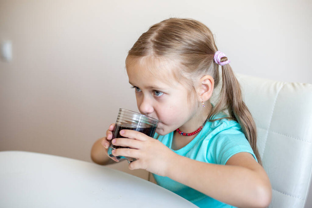 Happy little girl drinking soda from glass - Zdjęcie, obraz