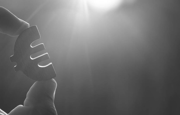 man's hand holding  the Euro icon silhouette against  sky. - Foto, Bild