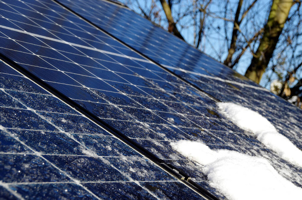 Kar ve buzla kaplı güneş panelleri. Evin çatısında fotovoltaik elektrik tesisatı var. Güneşli bir günde kış mevsimi. Düşük performans ve verimlilikle alternatif PV enerji üretimi. - Fotoğraf, Görsel