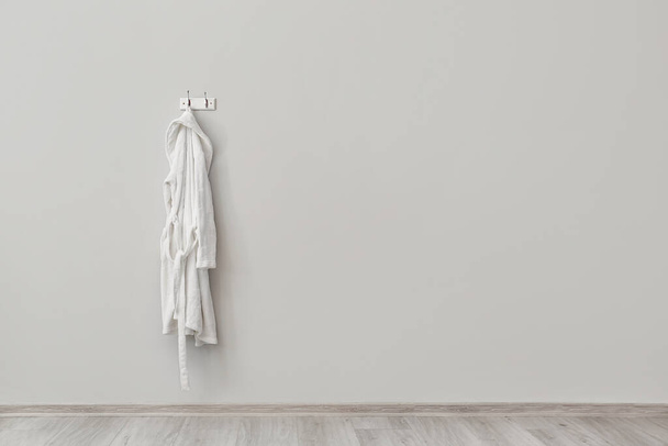Valkoinen kylpytakki roikkuu kevyellä seinällä - Valokuva, kuva
