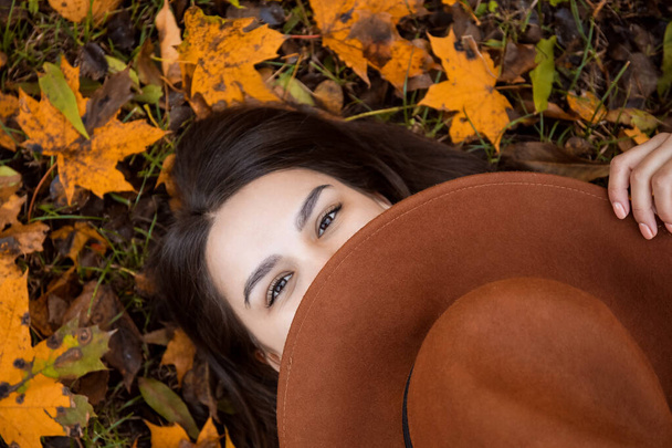 Gyönyörű nő takaró arc filc kalap őszi parkban - Fotó, kép