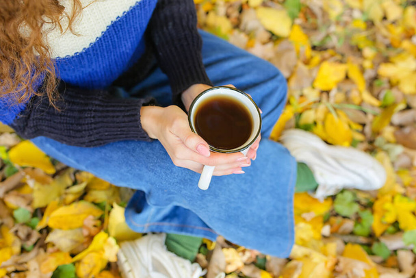 Woman holding cup of tea in autumn park - Fotó, kép