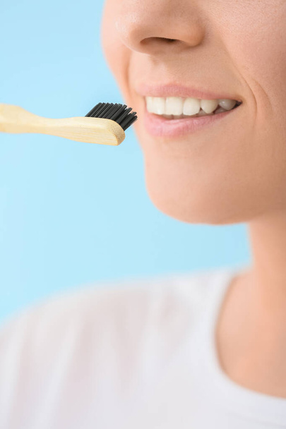 Woman with bamboo tooth brush on blue background, closeup - Foto, immagini