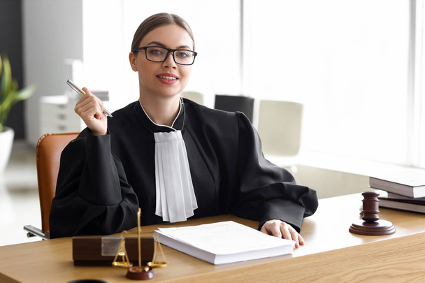 Жінка-суддя з документами на робочому місці в залі суду
 - Фото, зображення