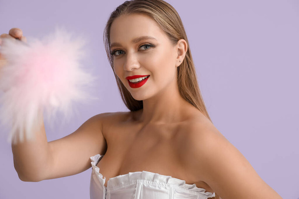 Attractive woman with feather stick from sex shop on color background - Photo, Image