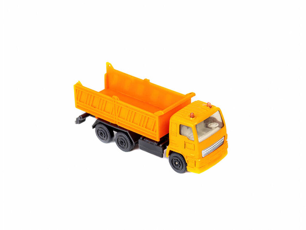 Orangefarbener Kipper - Kinderspielzeug auf weißem Hintergrund. - Foto, Bild