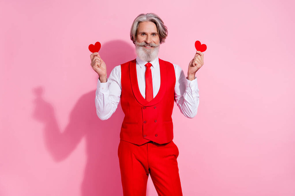 Portrait of attractive cheery grey-haired man holding in hands small heart cards isolated over pink pastel color background - Fotoğraf, Görsel