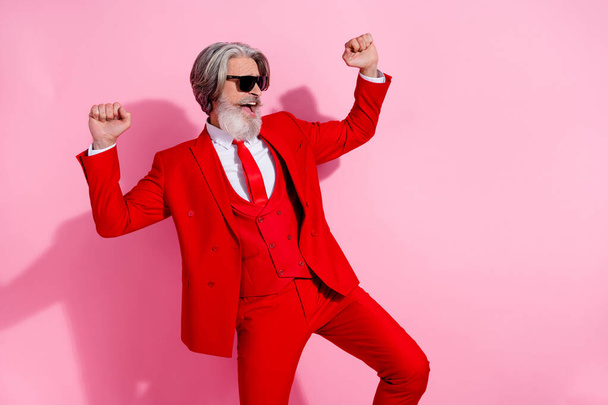 Photo of pretty lucky man pensioner dressed red jacket dancing rising fists empty space isolated pink color background - 写真・画像