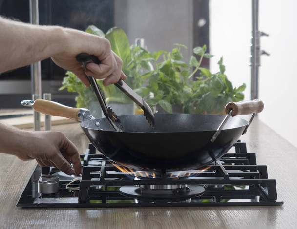Frying pan on a gas stove. Chef controls the cooking process.cooking on a gas stove. expensive gas in Europe. - 写真・画像