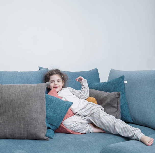 little girl sitting on sofa and looking at camera - Фото, изображение