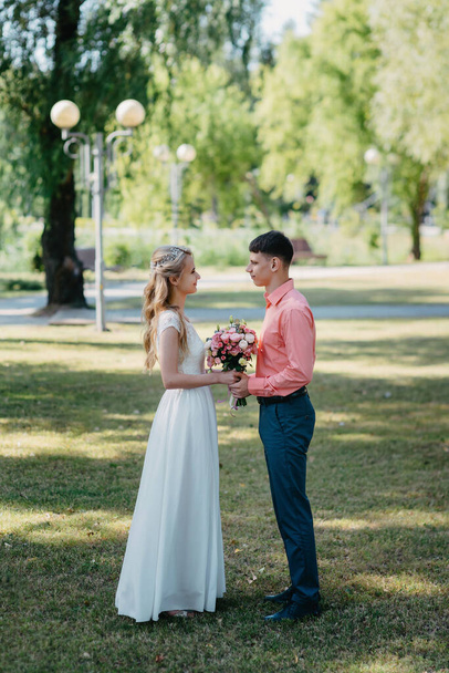 Bride and groom at wedding Day walking Outdoors on spring nature. Bridal couple, Happy Newlywed woman and man embracing in green park. Loving wedding couple outdoor. Wedding shot of bride and groom in - Φωτογραφία, εικόνα