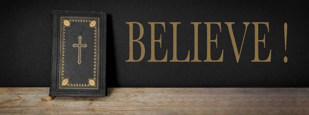 CREER - Iglesia fe cristiana fondo pancarta panorama - Antigua Biblia santa con cruz de oro en la antigua mesa de madera vintage rústico y pared negro - Foto, imagen