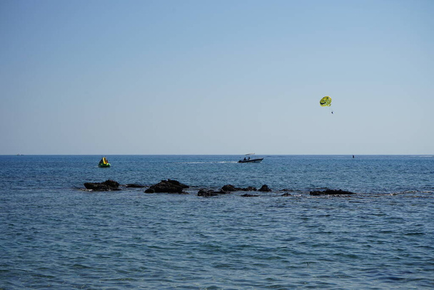 Parasailing w basenie Morza Śródziemnego. Parasailing jest rekreacyjna działalność kiting, gdzie osoba jest holowana za pojazdem podczas przymocowania do specjalnie zaprojektowanego skrzydła baldachimowego, który przypomina spadochron. Kolimpia, Rodos, Grecja  - Zdjęcie, obraz