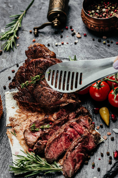 Grilled beef steak with on dark background. Steak Ribeye Black Angus medium rare beef. vertical image. top view. place for text. - Фото, зображення