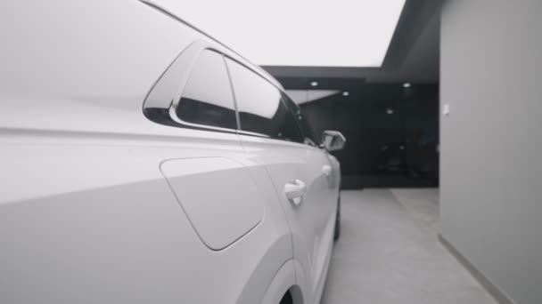 Sivunäkymä uuden valkoisen auton varastossa. Toimintaa. Kaunis ulkonäkö uuden valkoisen auton myyntisalongissa. Tyylikäs pitkä auto myytävänä - Materiaali, video