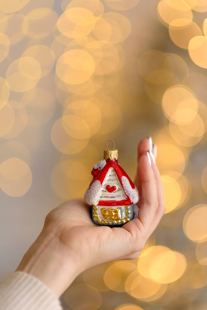 Decoración del árbol de Navidad en forma de casa en una hermosa mano femenina. Preparación para la Navidad - Foto, imagen