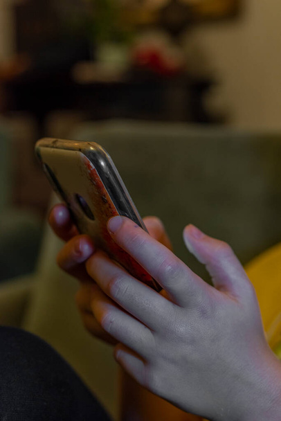 Παιδικό χέρι με κινητό τηλέφωνο σε χρώμα σκούρο εσωτερικό - Φωτογραφία, εικόνα