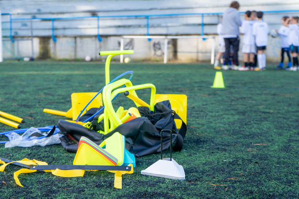 Many untidy soccer training implements littering the field. Group of unfocused children talking to their coach. - Fotó, kép