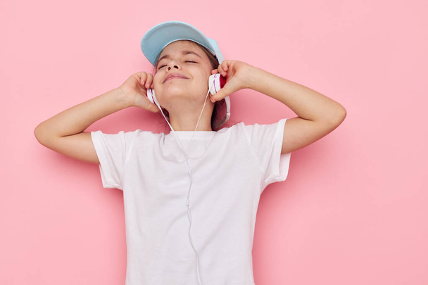 Portrait of happy smiling child girl listening to music on headphones isolated background - Foto, Imagem