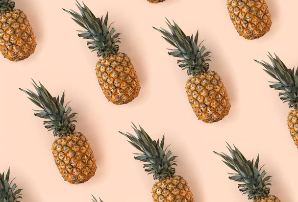 Helder patroon van vele ananas op een trendy zachte beige roze achtergrond  - Foto, afbeelding