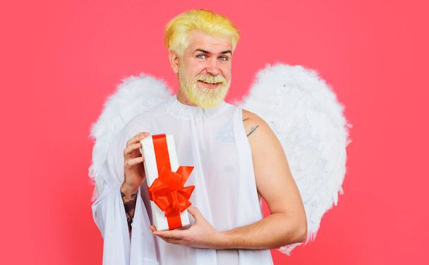 Feliz día de San Valentín. Hombre sonriente con caja de regalo. Ángel Cupido con alas blancas. San Valentín presente. - Foto, imagen