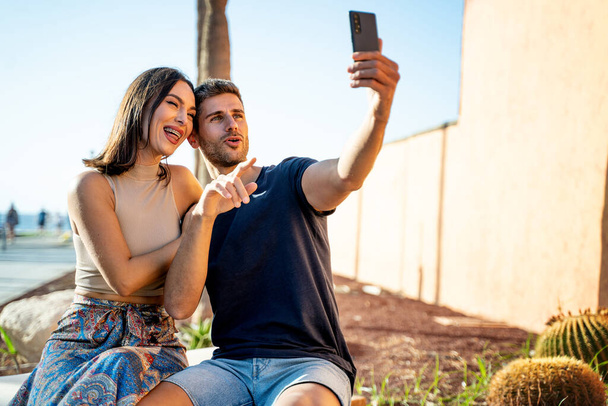 Young happy couple taking selfie with mobile phone, smiling to the smartphone. Summer time. Vacation. Traveler. Real people lifestyle. - Foto, imagen