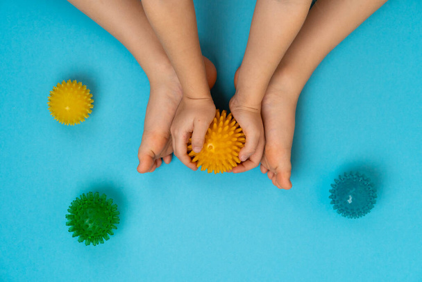 boules d'aiguille colorées pour le massage et la physiothérapie sur un fond bleu avec l'image des pieds des enfants, le concept de prévention et de traitement des hallux valgus - Photo, image