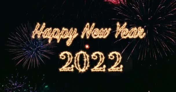 Gelukkig nieuwjaar 2022 geschreven met Sparkle vuurwerk op de lucht en brandende bengaalse lichten en vuurwerk op de achtergrond - Video