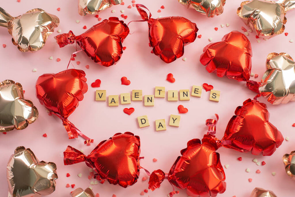 Sevgililer Günü kelimesi mektup bloklarından ve kırmızı kalplerden geliyor. Etrafta balonlar uçuşuyor.. - Fotoğraf, Görsel