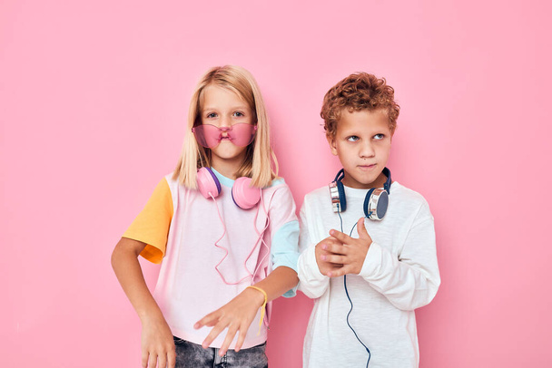 funny little boy and girl wearing headphones posing pink color background - Photo, Image