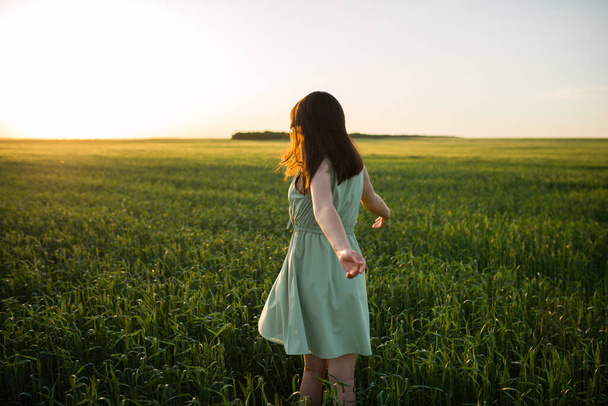 joven, hermosa chica asiática en un campo de trigo verde en el fondo de la puesta del sol
 - Foto, Imagen