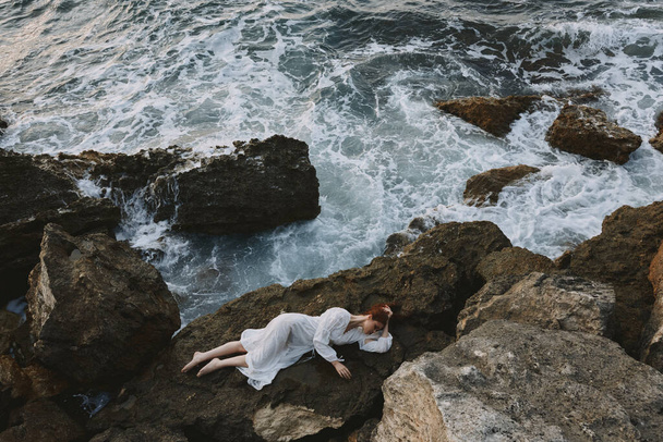 Mezítláb nő fehér ruhában feküdt egy kövön egy fehér ruha nyaralás koncepció - Fotó, kép